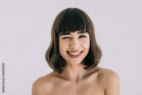Young woman smiling and winking isolated on white background