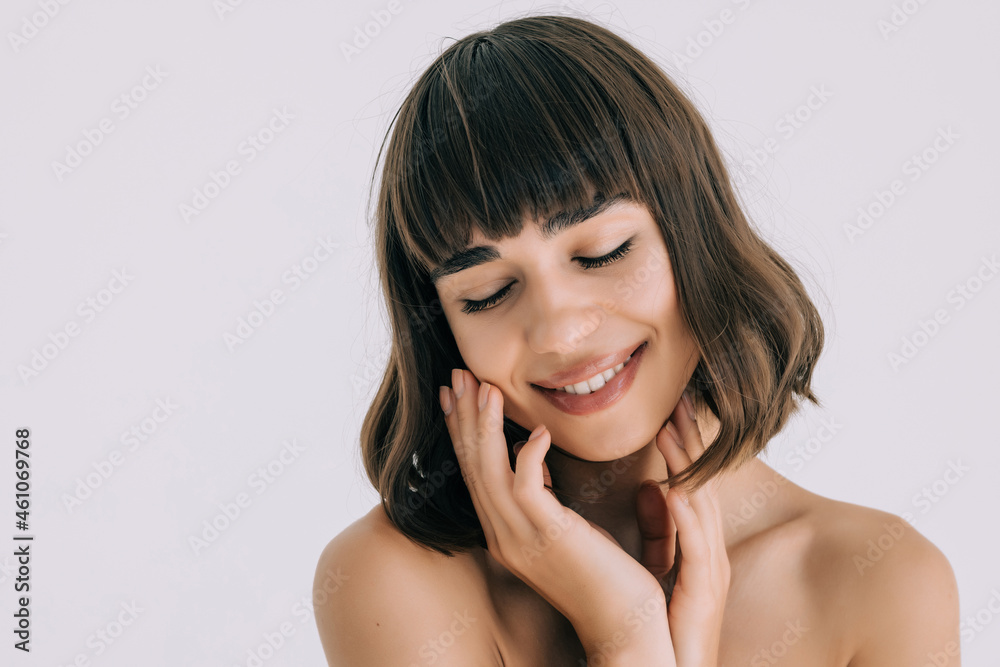 Beautiful young woman with perfect clean skin smiling touching hair over white wall. Facial treatment. Beautiful young woman with perfect clean skin smiling touching hair over white wall. Facial treatment.