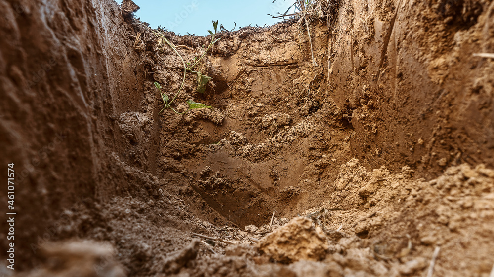 Obraz premium Dig a trench. Earthworks, digging trench. Long earthen trench dug to lay pipe or optical fiber. Construction the sewage and drainage. View from the trench. Clay soil. Part of the image is blurred