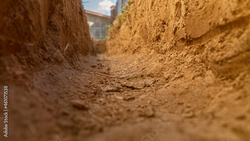 Dig a trench. Earthworks, digging trench. Long earthen trench dug to lay pipe or optical fiber. Construction the sewage and drainage. View from the trench. Clay soil. Part of the image is blurred photo