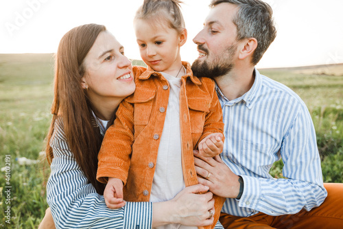 A hipster family walks in a summer field.
