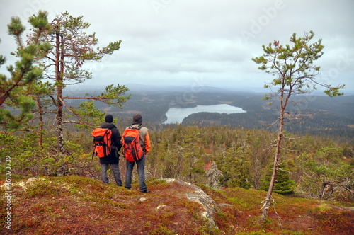 Two hikers with backpacks standing on the peak of rocky mountain Kivakka in Paanajarvi national park, amazing landscapes of Karelia photo