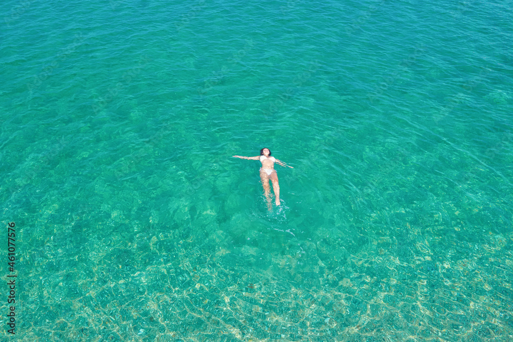 Young woman in a bikini swimming in sea water on the beach. View from above. Top, drone view