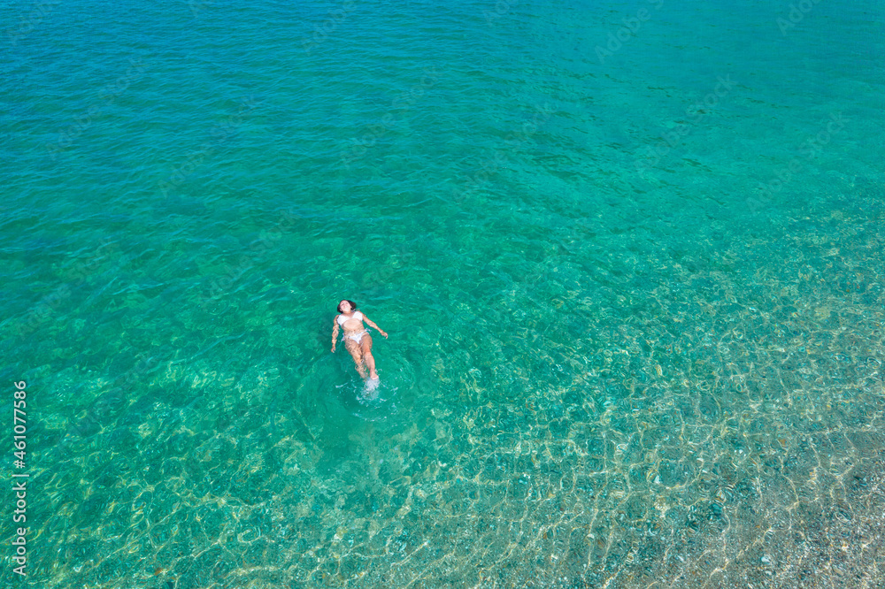 Young woman in a swimsuit lying on sea water on the beach. View from above. Top, drone view