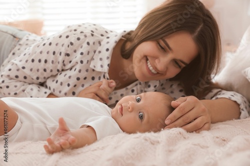 Mother with her cute baby on bed at home