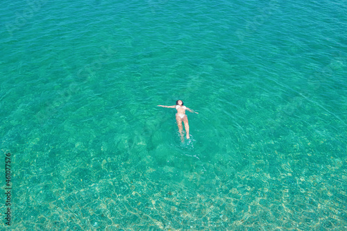 Young woman in a bikini swimming in sea water on the beach. View from above. Top, drone view