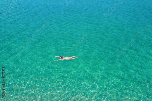 Young woman in a bikini swimming in sea water on the beach. View from above. Top, drone view