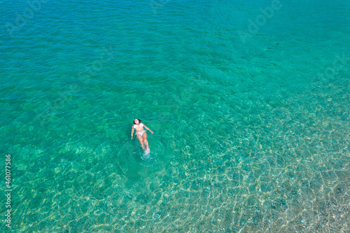 Young woman in a swimsuit lying on sea water on the beach. View from above. Top, drone view