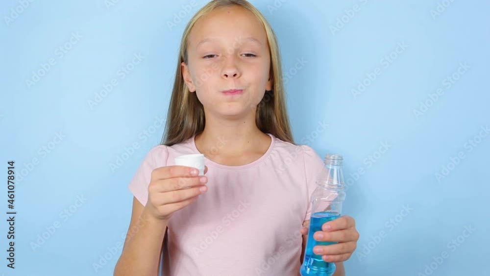 Girl uses mouthwash on a blue background close-up Girl uses mouthwash on a blue background close-up