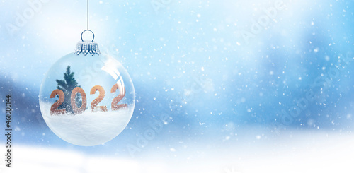 Schneekugel mit Ziffern 2022 vor unscharfem Hintergrund