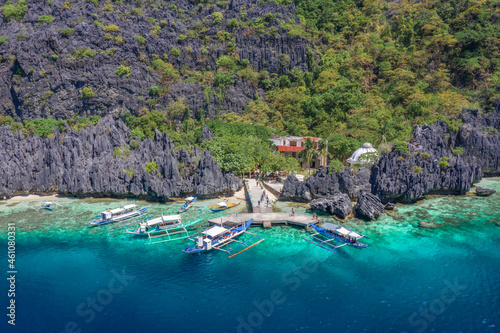 Beautiful coral reef, boats and a clear ocean on Matinloc Island, Bacuit Archipelago, El Nido, Palawan, Philippines. Aerial drone view.