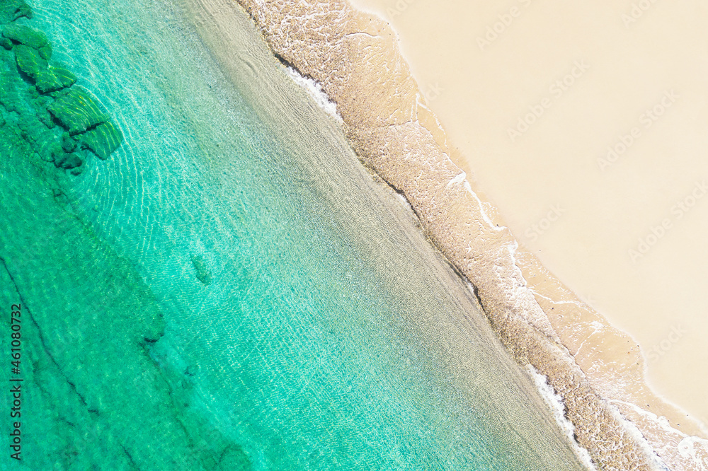 Relaxing aerial beach view with calm sea water and stone, slabs, lump, coral. Summer vacation. Blue ocean lagoon, sea shore, coastline. Drone, copter top view.