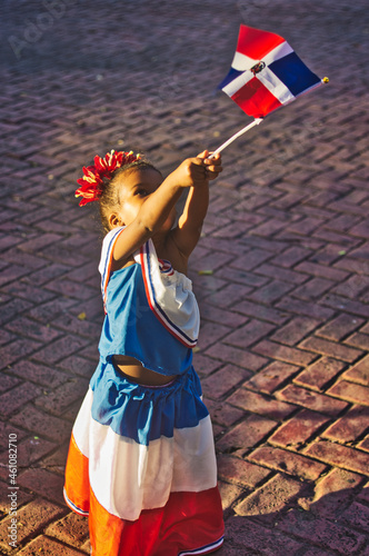 Niña Dominicana levantando la bandera hacia el cielo 
