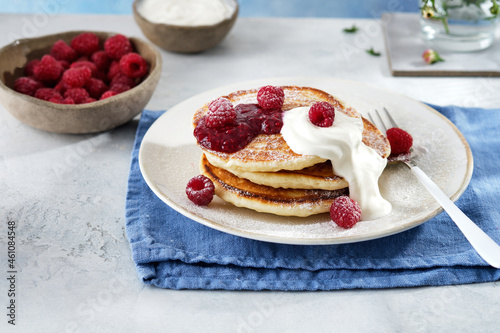 Pancakes for breakfast with sour cream, raspberry jam and fresh raspberries.