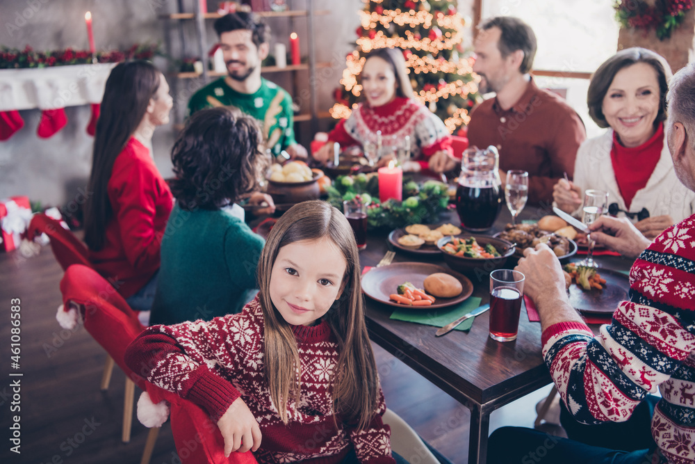 Fototapeta premium Photo portrait little girl wearing sweater celebrating winter holidays with family sitting at table on new year