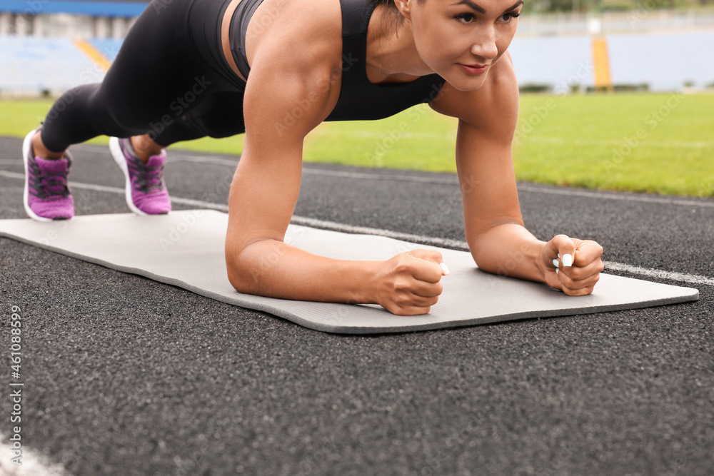 Fototapeta premium Young woman doing plank exercise at stadium, closeup