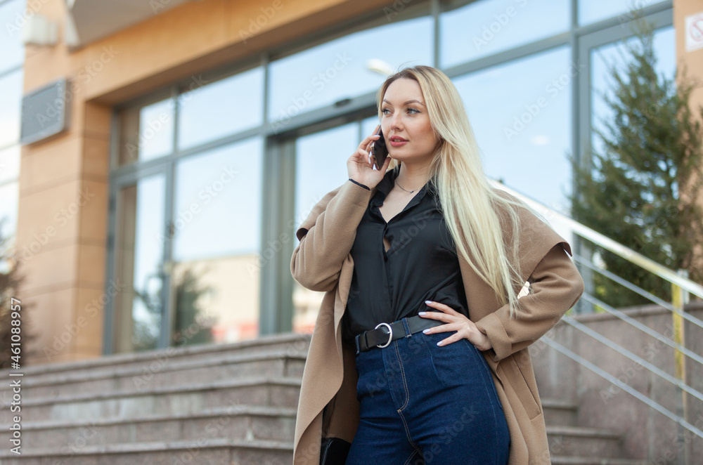 Young blonde business lady talking on the phone in city