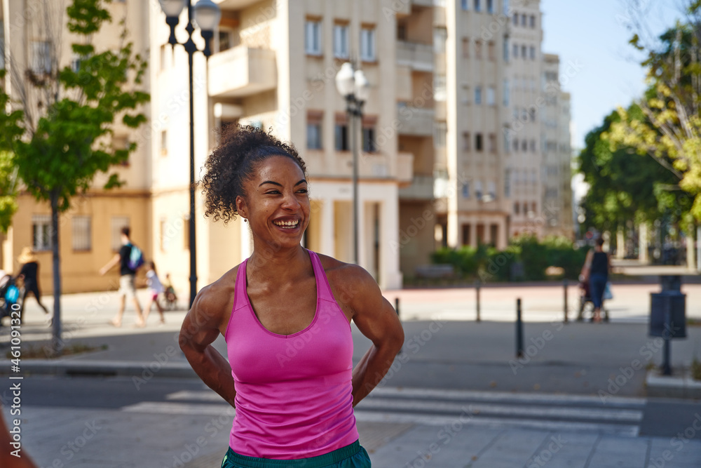 Athletic young woman smiling cheerfully outdoors