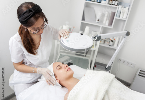Skincare treatment. Dermatologist carefully examines the client s face before the cosmetic procedure in beauty salon