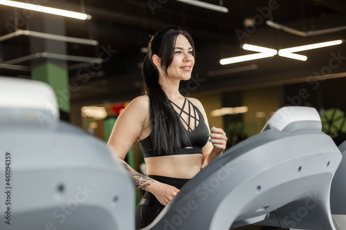 Young fitness woman doing cardio workout on a treadmill in a modern gym. Healthy lifestyle, sport concept