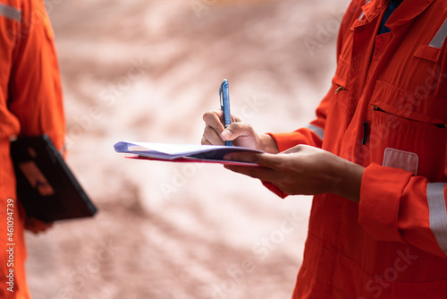 Foto Action of safety officer is writing and check on checklist document during safety audit and inspection at drilling site operation