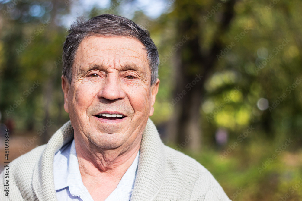 Portrait of happy senior man standing in the park. Elder health and retirement concept Portrait of happy senior man standing in the park. Elder health and retirement concept