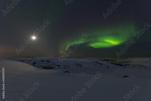 In winter, the moon and the aurora borealis are in the sky. © Moroshka
