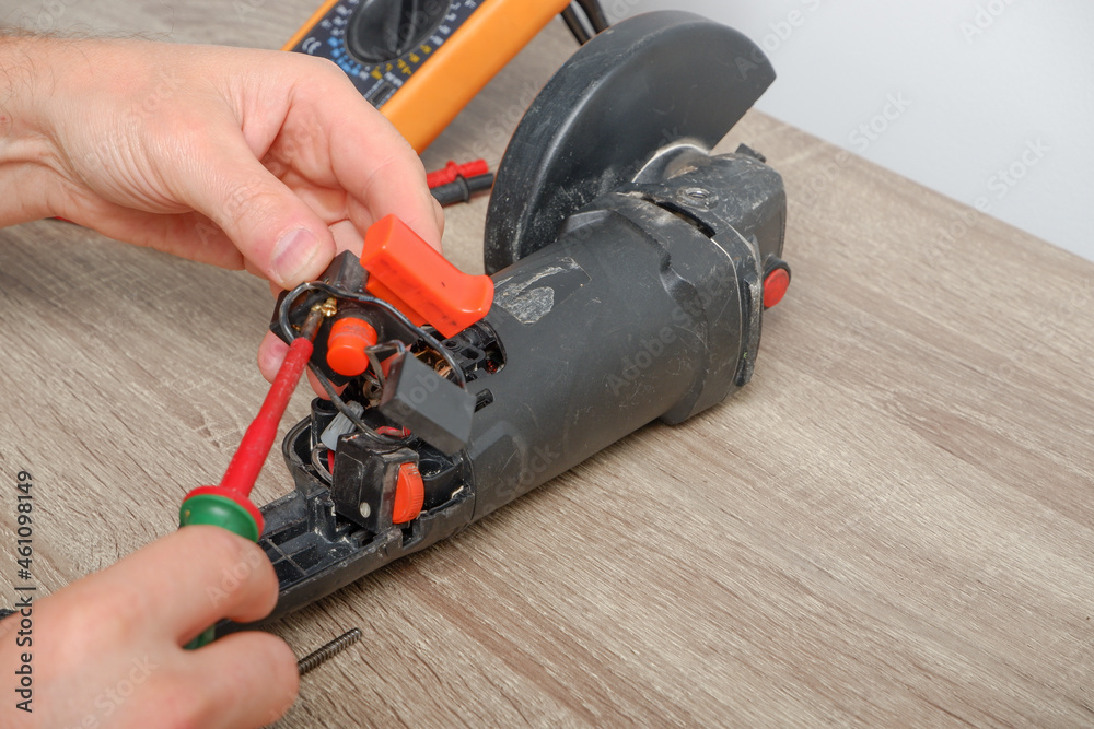 Power tool repair. An engineer repairing an angle grinder. Assembling the tool in the process of repair. Power tool repair. An engineer repairing an angle grinder. Assembling the tool in the process of repair.