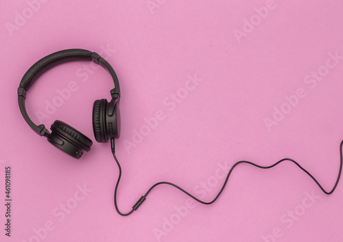 Cable black stereo headphones on pink background. Top view