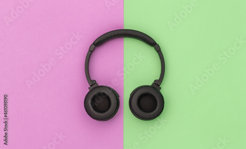 Wireless stereo headphones on pink green background. Top view