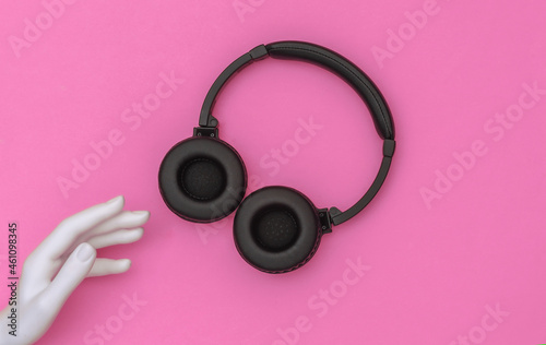 The mannequin's white hand touches headphones on pink background. Top view