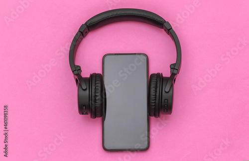 Smartphone with wireless stereo headphones on pink background. Top view
