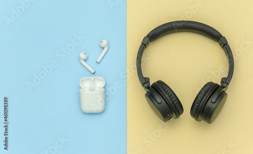 Wireless large stereo headphones and small earbuds with charger case on yellow blue pastel background. Top view