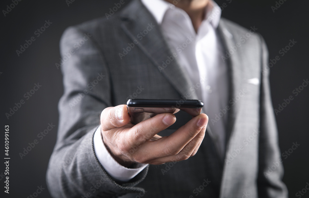 Businessman holding smartphone in office. Businessman holding smartphone in office.