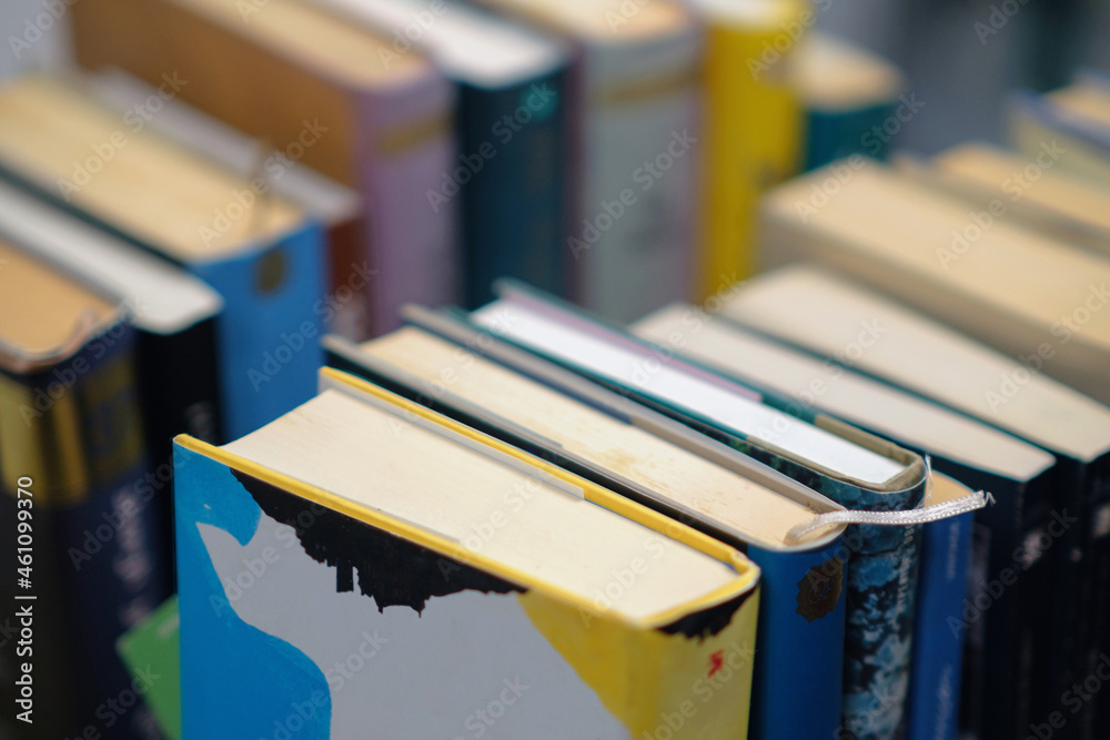 A stack of used books of different thicknesses on the shelf in the library, selective focus A stack of used books of different thicknesses on the shelf in the library, selective focus