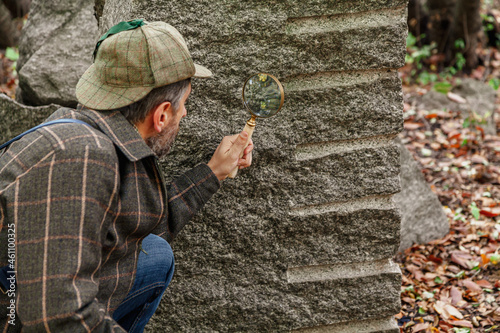 Scientist examines block of sandstone through magnifying glass