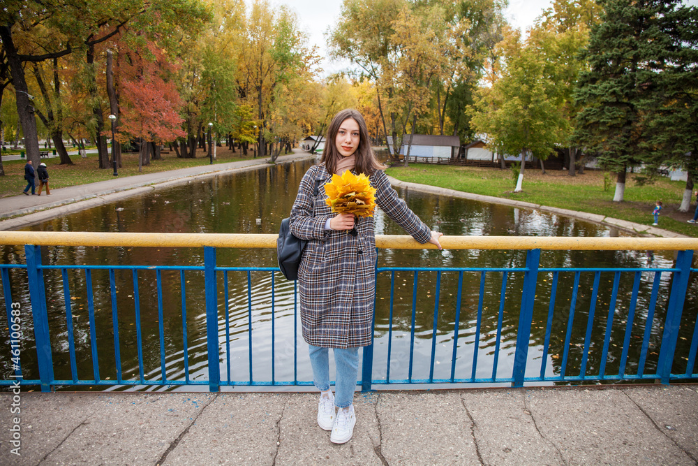Young beautiful brunette girl walking in autumn park