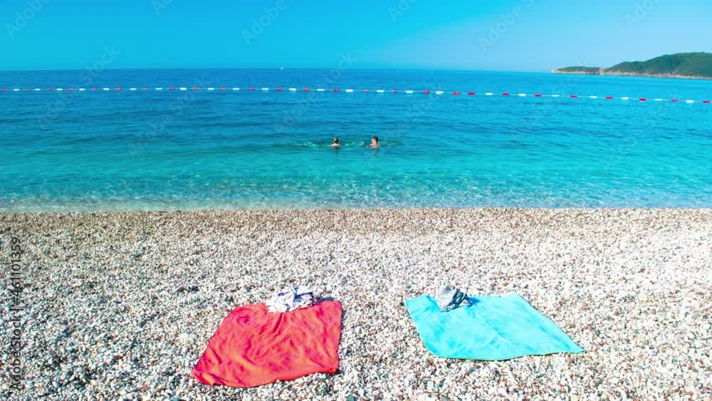 4k On the beach. Young caucasian guy and girl appear on a pebble beach and swim in the blue calm clear sea on a sunny summer morning. Concept of a seaside vacation. Stop motion animation. 4k On the beach. Young caucasian guy and girl appear on a pebble beach and swim in the blue calm clear sea on a sunny summer morning. Concept of a seaside vacation. Stop motion animation.