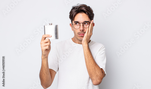 young hispanic man feeling bored, frustrated and sleepy after a tiresome. alcohol flask concept photo