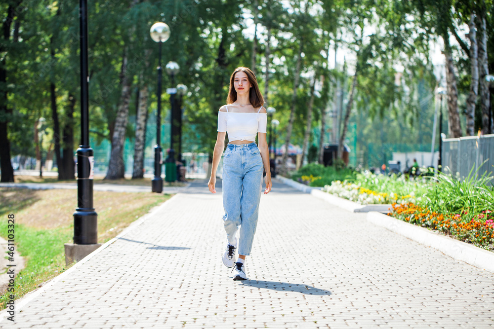 Young beautiful brunette girl walking in a summer park