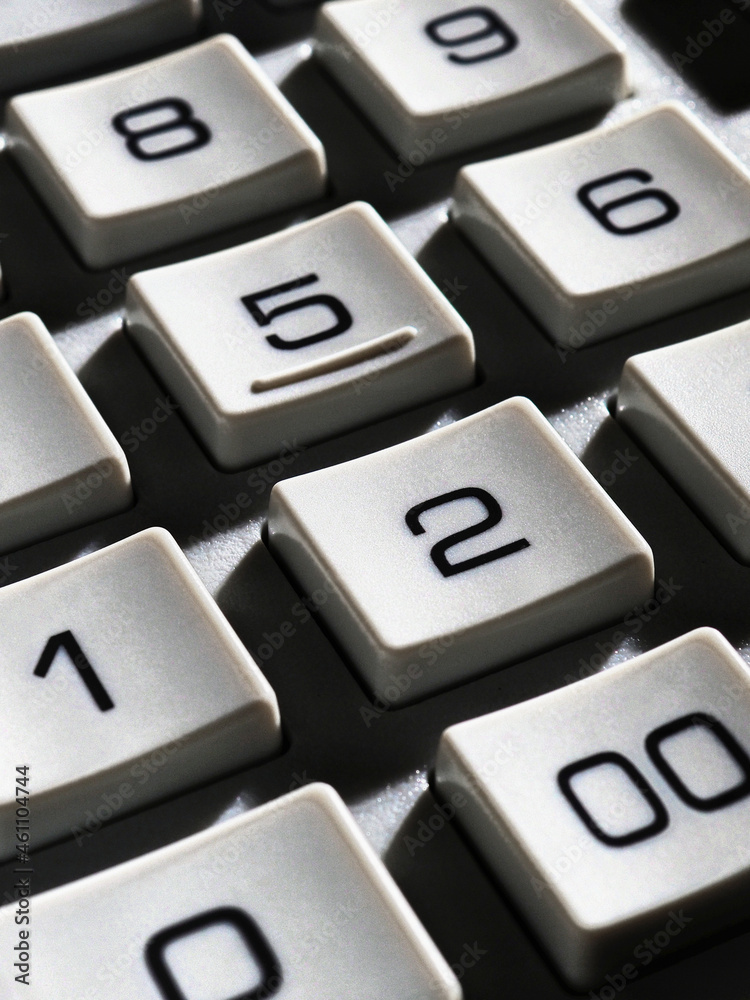 Calculator keyboard buttons close-up. Dark dramatic vertical illustration with harsh light and deep shadows. Economy, finance, money, commerce. Business project, calculations and decision making Calculator keyboard buttons close-up. Dark dramatic vertical illustration with harsh light and deep shadows. Economy, finance, money, commerce. Business project, calculations and decision making
