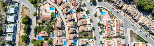Cropped panoramic image Pinar de Campoverde residential district view from above. Drone point of view luxury summer villas with swimming pools townscape rooftops. Costa Blanca, Alicante, Spain
 photo