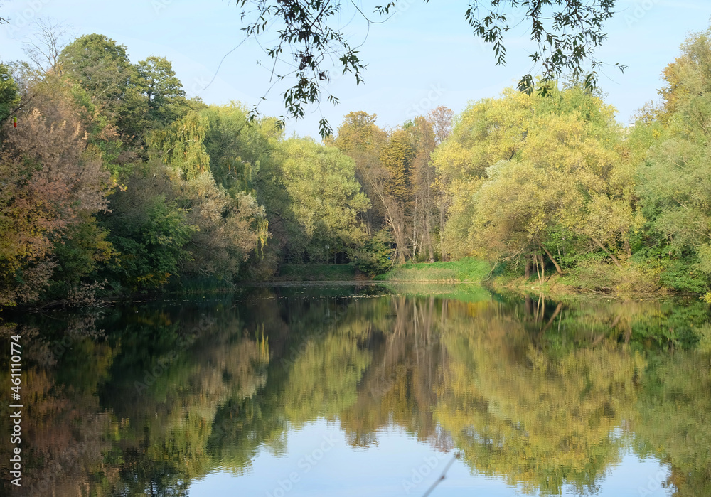 Autumn landscape with a pond and trees on the shore, selective focus, horizontal orientation. Autumn landscape with a pond and trees on the shore, selective focus, horizontal orientation.