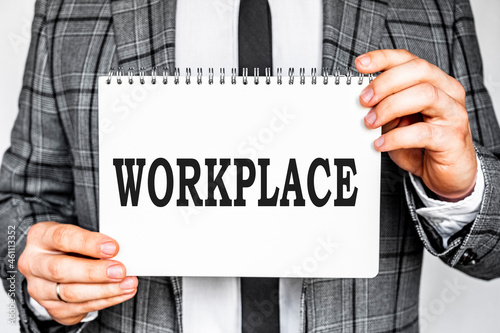 business, technology, internet and networking concept - businessman in gray fashionable business suit holding a white notebook with conference inscription WORKPLACE inscription