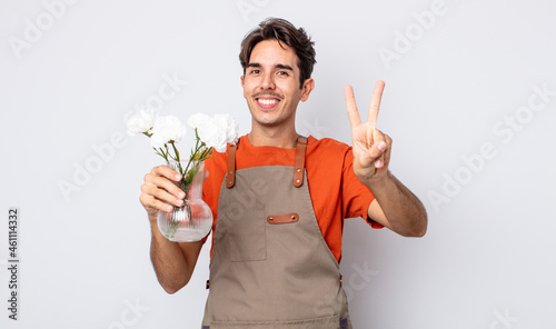 young hispanic man smiling and looking friendly, showing number two. florist concept photo