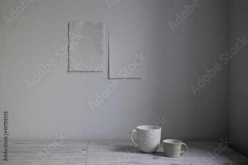 Scandinavian style. Interior Design. A white cups is on the table. Two blank sheets of paper are attached to the wall. Empty space for text