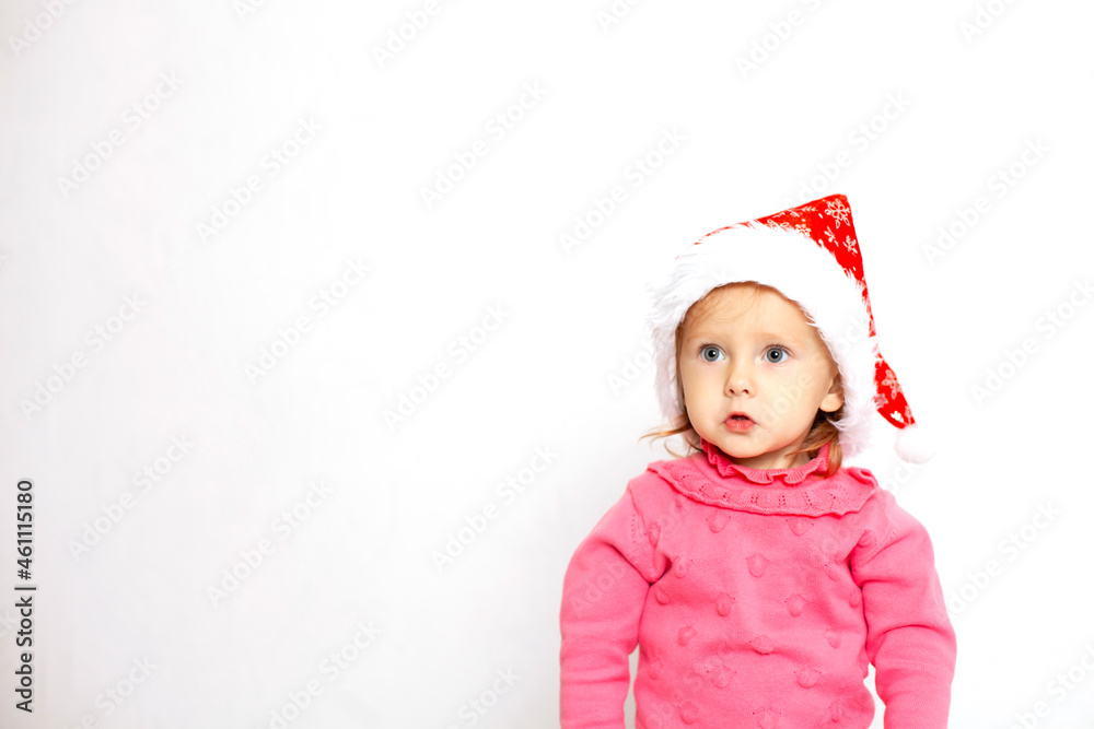 Portrait of a cute girl with blue eyes in a Christmas cap and a pink jumper. White background, space for text. New Year Portrait of a cute girl with blue eyes in a Christmas cap and a pink jumper. White background, space for text. New Year