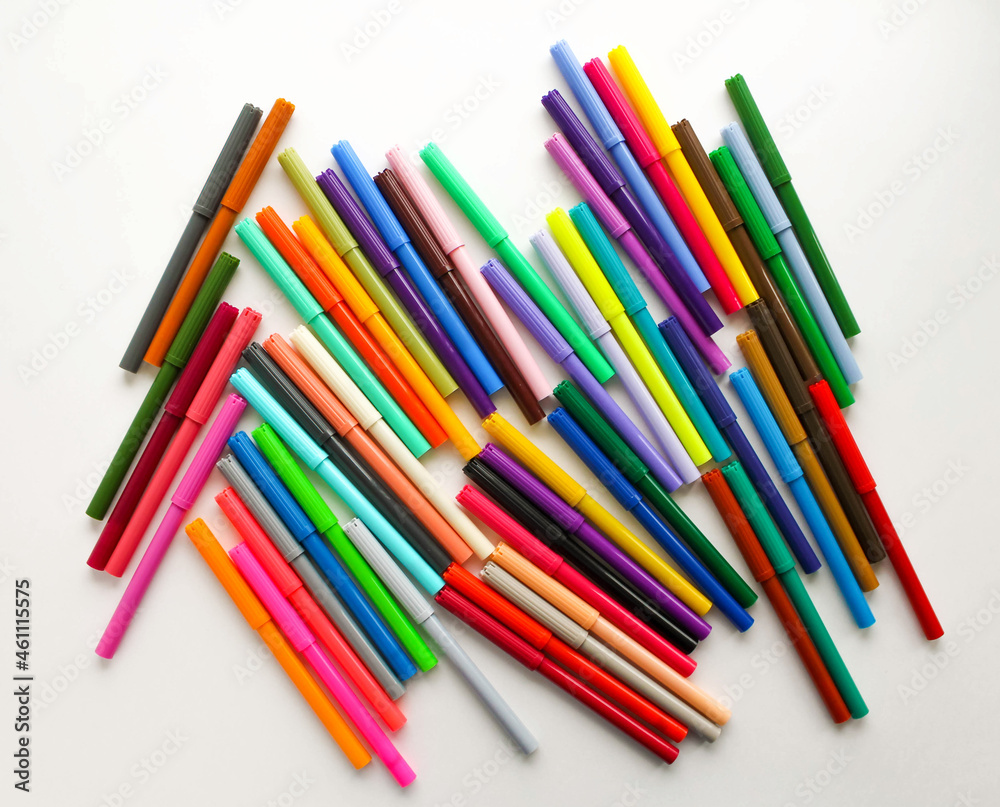 A bunch of colorful markers on a white background, top view. 