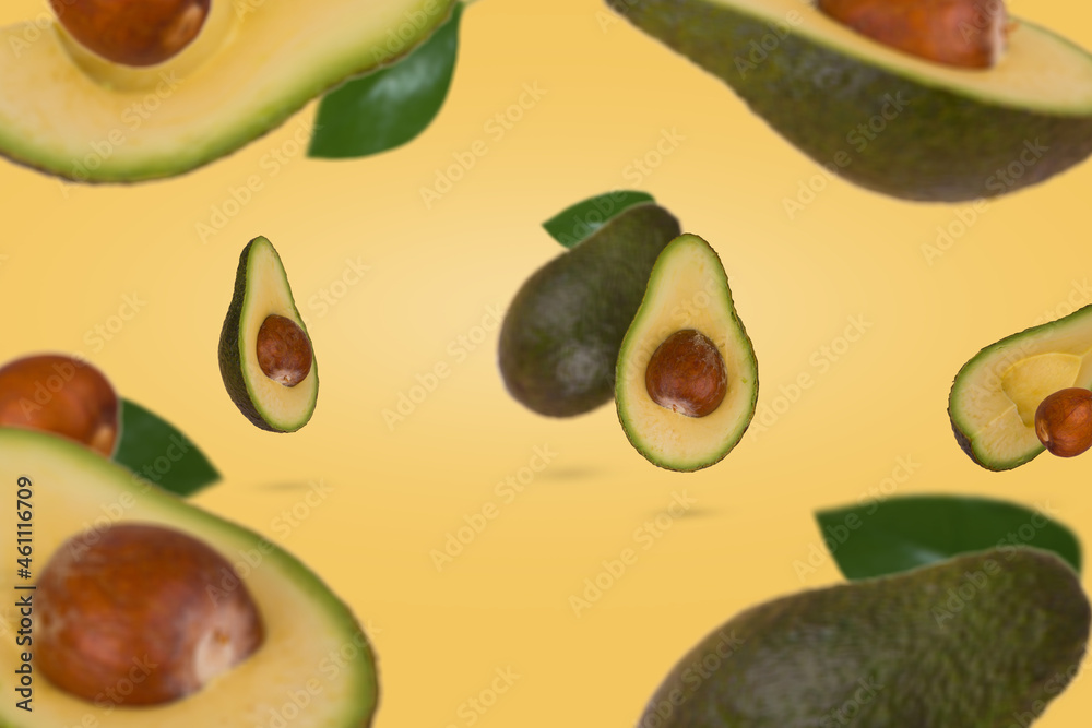 Fresh ripe whole and sliced avocado flying in air isolated on pastel yellow background. Fresh ripe whole and sliced avocado flying in air isolated on pastel yellow background.