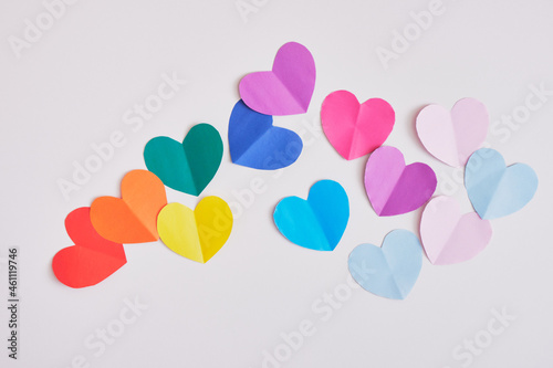 rainbow colored paper hearts on grey background, pride concept